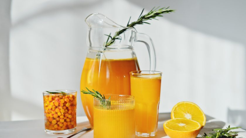 raw sea buckthorn and orange juice in glasses. with rosemary. antioxidant drink for immunity